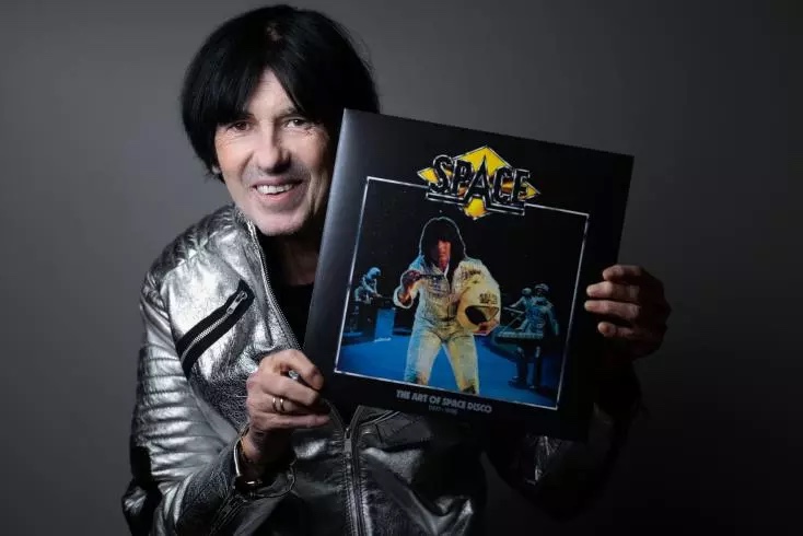 Didier Marouani, en veste argentée, tient le vinyle The Art of Space Disco